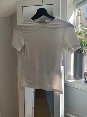 Vit basic t-shirt  - Vit tajt T-shirt från Weekday i storlek S. Säljer då den inte kommer till användning.