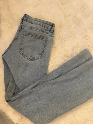 Ljusblå utsvängda lågmidjade   jeans i denim - Säljer ett par ljusblå jeans i klassisk utsvängd  modell med fem fickor och hög midja. Jeansen har en snygg tvättad look och är tillverkade i denim. Perfekta att matcha med en hoodie eller t-shirt för en avslappnad stil. Är uppsydda passar mig som är 158 perfekt