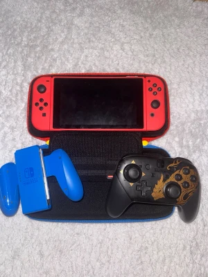 Nintendo Switch röd med Kontroll och 2 spel - Docket kommer också med och den är helt röd. Nintendo Switch Mario edition. Inte använd mycket eftersom jag inte har tid. Du får en extra kontroll monster hunter edition. Två spel, Super Smash Bros och Mario Kart 8.