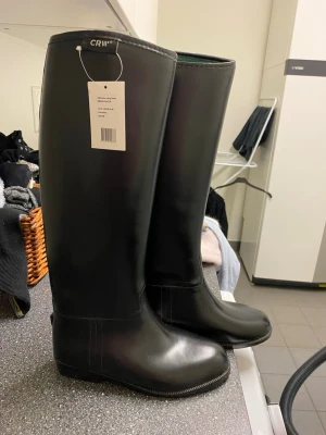 Svarta ridstövlar!💚🖤 - Stilrena svarta stövlar från CRW i storlek 36. De är höga med en klassisk rak form och har en grön insida. Tillverkade i ett tåligt material som passar perfekt för regniga dagar i stallet . Helt nya. Pris diskuteras 