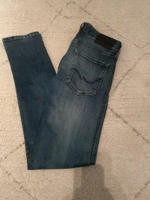 Jack & Jones Jeans Slim Glenn - Säljer ett par riktigt snygga slim jeans från Jack & Jones. Jeansen är helt nya och endast testade en gång, så de är i perfekt skick utan några som helst defekter. Modellen är slim fit vilket ger en modern och stilren passform som sitter riktigt bra på kroppen. Perfekta både till vardags och lite mer uppklädda tillfällen. Materialet är bekvämt och följsamt, vilket gör dem sköna att ha på sig hela dagen. Säljer dem tyvärr eftersom de var för små för mig, annars hade jag absolut behållit dem själv