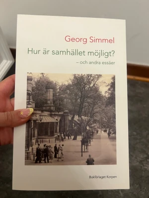 Hur är samhället möjligt? av Simmel - En bok av Georg Simmel med titeln 'Hur är samhället möjligt? – och andra essäer'. Omslaget är vitt med en svartvit bild av en stadsmiljö och grön samt röd text. Perfekt för dig som gillar samhällsfilosofi och essäer.