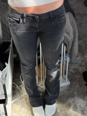 Mörkgrå bootcut jeans med slitningar - W 25 L 32Säljer ett par mörkgrå bootcut jeans med diskreta slitningar. Midjemått ca 38 cm, innerbenslängd ca 78cm. Dom är stretchiga så uppskattar att de passar alla från midjemått 36-42cm, tack! 🙏🏼 