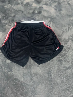 Tommy Hilfiger Retro Mesh-shorts - -Riktigt feta och unika sportshorts från Tommy Hilfiger i luftig mesh. Klassisk retro-look med röda/vita ränder på sidorna och broderad flagga. Dessa är tillverkade i USA, nytvättade och helt felfria. •  Skick: 10/10 