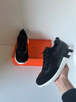 Svarta  sneakers med vit sula - Snygga svarta sneakers från  med chunky vit sula och svarta detaljer. Skorna har en modern design med blandning av läder och mocka, samt klassisk snörning. Perfekta för dig som vill ha en exklusiv och trendig look.