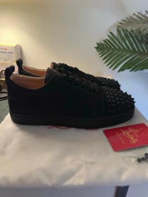 Svarta Louboutin sneakers med nitar - Säljer ett par svarta sneakers från Christian Louboutin med nitar. Perfekta för dig som vill sticka ut med en edgy och lyxig stil.