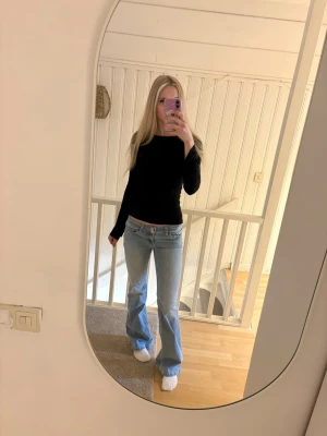 Ljusblå bootcut jeans med brodyr - Säljer ett par ljusblå bootcut jeans med låg midja och rosa broderade detaljer på bakfickorna från Nelly. Jeansen har klassisk femficksmodell och är tillverkade i denim med lätt tvättad look. Perfekta för en avslappnad och trendig stil.