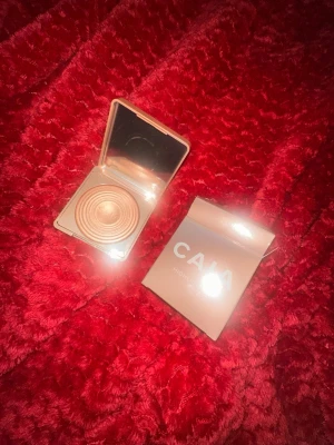 CAIA highlighter i CANNES - Highlighter från CAIA i en snygg guldig nyans. Kommer i en fyrkantig dosa med spegel och har ett coolt cirkelmönster i pudret. Perfekt för att ge glow till kindbenen. Förpackningen är stilren och rosa. Helt oanvänd och ny. 