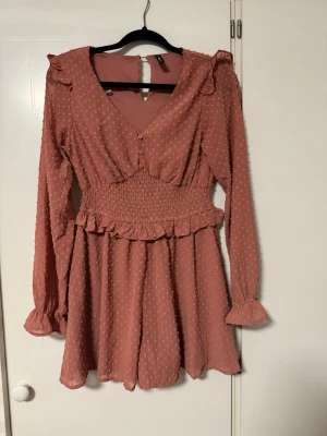 Jumpsuit/klänning - Söt rosa jumpsuit men ser ut som en klänning från New Yorker med långa ärmar och volangdetaljer vid axlarna. Passar alla tillfällen. Endast använd en gång.