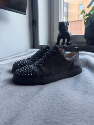 Christian Louboutin skor - Säljer ett par gråa sneakers från Christian Louboutin med klassiska röda sulor och coola nitar på tårna. Skicket är bra dock använda men inget man riktigt ser, priset går alltid att diskuteras, box kommer inte 