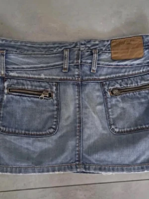 Blå jeanskjol - Snygg blå jeanskjol i kort modell med två framfickor och två bakfickor med dragkedjor. Kjolen har bälteshällor och klassiska jeansdetaljer som kontrastsömmar och knappstängning framtill. Perfekt till vardags för en avslappnad look. Skiit snygg kjol till sommaren😍Ge gärna prisförslag💞