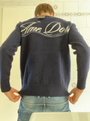 Mörkblå stickad tröja Ame Doree - Mörkblå stickad tröja från Ame doree med broderad logga på bröstet och stor vit text på ryggen. Tröjan har rund hals, långa ärmar och ribbade muddar vid ärmslut och nederkant. Perfekt för dig som gillar enkel men snygg stil. Tröjan är aldrig använd. Nypris 850, mitt pris 699. Väldigt bekväm passform. Hör av er vid minsta fundering😁