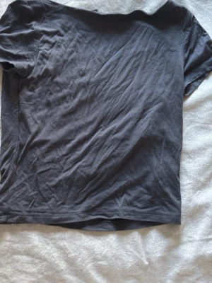 Mörkgrå basic t-shirt - En enkel mörkgrå t-shirt i mjuk bomull. Klassisk passform med korta ärmar och rund halsringning. Perfekt att matcha med jeans eller shorts för en clean look.