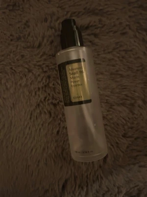 COSRX Snail 96 Mucin Power Essence - Populär toner från COSRX med snigelsekret, Advanced Snail 96 Mucin Power Essence. Kommer i en genomskinlig plastflaska med svart pump och etikett. Perfekt för dig som vill boosta återfuktningen i din hudvårdsrutin.
