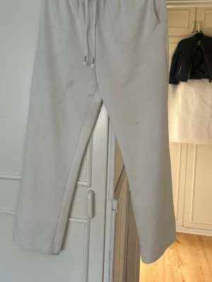 Beiga mjukisbyxor med dragsko - Säljer ett par beiga mjukisbyxor med rak passform och dragsko i midjan. Byxorna är tillverkade i mjukt material och har en enkel, clean look utan synliga loggor eller detaljer. Perfekta för chill dagar eller när du vill vara bekväm.