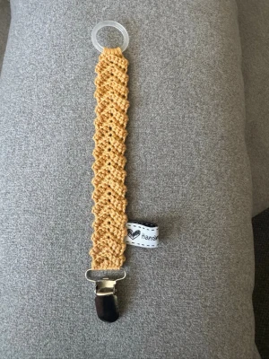 Virkad napphållare  - Virkad,guld/beige napphållare, virkad av mig i 100% bomullsgarn med metallclips och silikonring.  Mönsterskapare: animo.design 