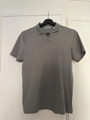 Grön polotröja - Säljer en stilren grön pike från Bläck. Polon är kortärmad och har en enkel, clean look som passar perfekt till jeans eller shorts. Materialet är mjukt och känns skönt mot huden.