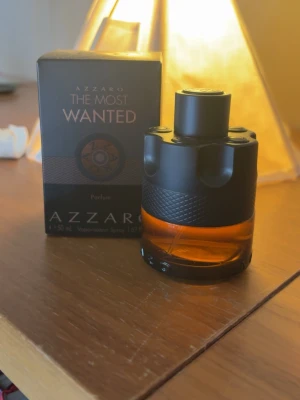 Azzaro The Most Wanted Parfum 50ml - Azzaro The Most Wanted Parfum i en cool, rund flaska med svart och bärnstensfärgat glas. Flaskan har en unik design som påminner om en revolvertrumma och känns riktigt lyxig. Kommer med originalkartong och rymmer 50 ml. (BARA BYTEN) eventuellt säljs för bra pris