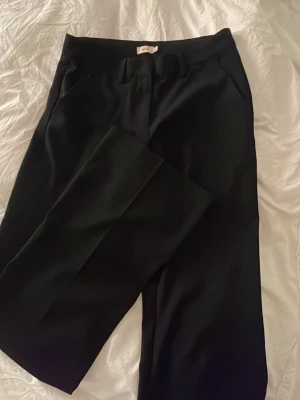 Svarta kostymbyxor från Nelly - Säljer dessa kostymbyxor som är helt slutsålda på Nelly de heter low waist flare suit pants och är köpta för 400kr de är i storlek 36 de är använda men knappt tecken på det 