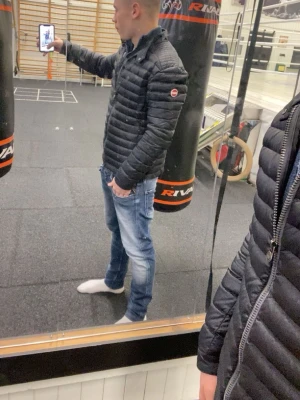 Colmar jacka  - Säljer en svart dunjacka med quiltad design och hög krage. Jackan har en diskret logga på ärmen och dragkedja framtill. Perfekt för kalla vinterdagar och ger en clean, sportig look.