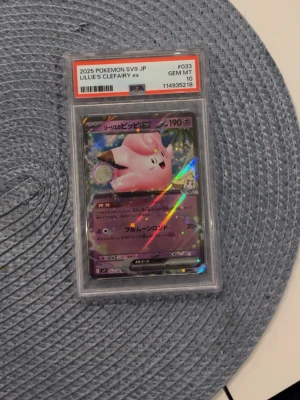 Intressekoll!!!! Pokémonkort Lillie's Clefairy ex JP  - Japanskt Pokémonkort Lillie's Clefairy ex från 2025, graderat PSA 10 GEM MINT. Kortet har holografisk yta och är inneslutet i ett skyddande plastfodral. Perfekt för samlare av Pokémonkort och anime-relaterade prylar. 