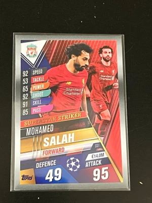 Match Attax Liverpool FC samlarkort - Samlarkort från Topps Match Attax med Mohamed Salah som forward för Liverpool FC. Kortet har färgstark design med statistik och klubbmärke, samt UEFA Champions League-logga. Perfekt för dig som gillar fotboll och samlarkort.