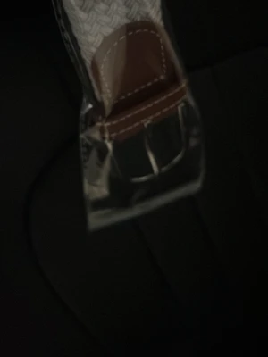 Vitt flätat bälte med skinn-detaljer - Snyggt vitt flätat bälte med bruna skinn-detaljer och silverfärgat spänne. Perfekt accessoar för att lyfta din outfit med en stilren touch. Bältet har en klassisk design och passar till många olika looks.