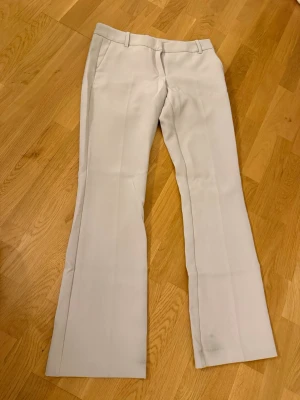 Beiga kostymbyxor lågmidjade - Snygga beiga kostymbyxor med lowwaist-modell och pressveck. Byxorna har hällor för skärp och fickor fram samt bak. Perfekta för en stilren look och passar till många olika outfits.