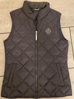 Gant väst - Vadderad väst från Gant. Mörkt marinblå. Junior stl 176, fungerar som XS/S. Välvårdad och jättefint skick, sparsamt använd.