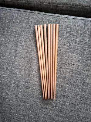 Bruna ätpinnar i trä, 4 - Säljer fyra par klassiska ätpinnar i trä. De är bruna, släta och har en avsmalnande form som gör dem enkla att använda till sushi, nudlar eller annan asiatisk mat. Perfekt till middagsbjudningar eller vardagsbruk.