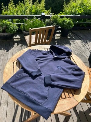 Mörkblå CD hoodie - Snygg mörkblå hoodie från CD med broderad logga på bröstet. Klassisk känguruficka framtill, ribbade muddar och mjukt material som känns riktigt skönt mot huden. Perfekt för dig som gillar en clean och stilren look.