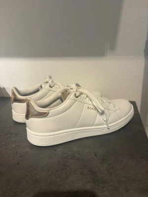 Vita sneakers från Björn Borg - Snygga vita sneakers från Björn Borg. Klassisk låg modell med vita snören och diskret logga på sidan. Ovandelen är i slätt syntetmaterial och sulan är vit. Perfekta för en clean och stilren look. Använda få gånger, därav att undersidan är smutsig.