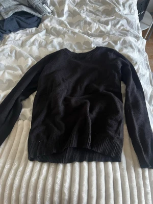 Svart stickad tröja från Vila - En enkel svart stickad tröja från Vila med rund halsringning och ribbade muddar vid ärmslut och nederkant. Perfekt basplagg till garderoben och lätt att matcha med olika stilar. Materialet känns mjukt och bekvämt.