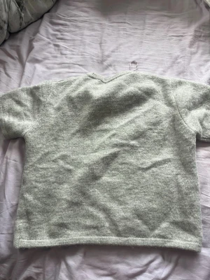 Ljusgrå stickad tröja Gina Tricot - Mysig ljusgrå stickad tröja från Gina Tricot. Tröjan har en enkel, rak passform med korta ärmar och ribbstickad nederkant. Perfekt för lager på lager och passar till det mesta i garderoben.