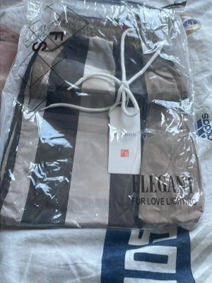  burberry och svarta shorts - Säljer ett par snygga shorts med breda vertikala ränder i beige, svart och en tunn röd detalj. Shortsen har resår i midjan och snörning för extra komfort. Perfekta för sommaren och har en avslappnad passform.