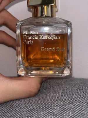 Maison Francis Kurkdjian Grand Soir Ca 60/70ml - Parfym från Maison Francis Kurkdjian, Grand Soir, i en elegant fyrkantig glasflaska med guldfärgad kork. Doften består av en lyxig blandning av amber och vanilj vilket ger en väldigt elegant och fantastisk doftprofil. Köpt som tidigare tester, så kommer utan orginalförpackning men med kork. Skriv gärna om du undrar någonting!