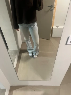 Ljusblå bootcut jeans - Säljer ett par ljusblå bootcut jeans med klassisk femficksdesign och normal midja. Jeansen har en avslappnad passform över låren och lätt utsvängda ben. Perfekta för en trendig och avslappnad look.