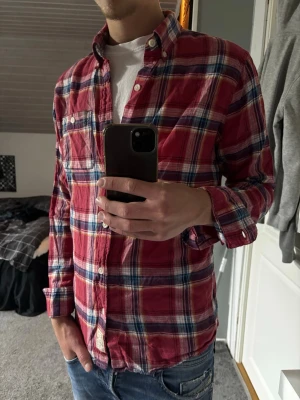Rutig Hollister linneskjorta - Säljer en röd, blå och vit rutig skjorta från Hollister i linnematerial. Skjortan har lång ärm, klassisk krage och knappar framtill. Perfekt för dig som gillar en avslappnad men ändå stilren look.