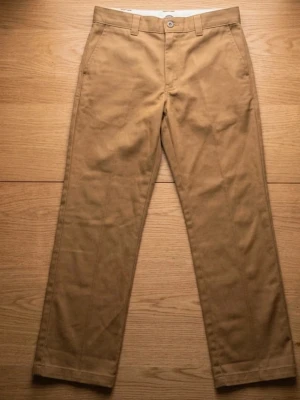 Beiga chinos från Dickies - Snygga beiga chinos från Dickis med rak passform och klassisk design. Byxorna har bälteshällor, knappgylf och två sidofickor. Tillverkade i ett mjukt bomullstyg som känns bekvämt hela dagen. Perfekta för en clean och stilren look.