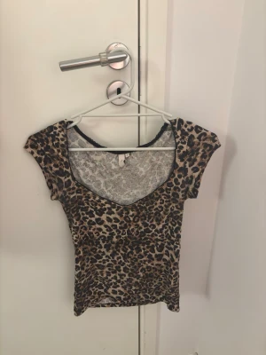 Topp från Nelly - Snygg leopardmönstrad topp från Nelly med v-ringning och korta ärmar. Använd enstaka gång (nyskick)