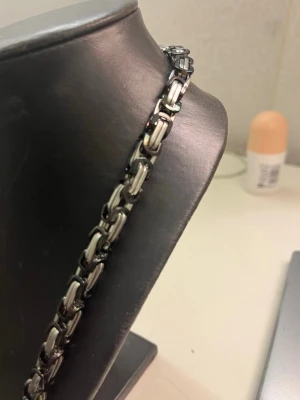 Kedjehalsband i rostfritt stål - Snyggt halsband med robust kedjedesign i silverfärgat rostfritt stål. Länkarna är rektangulära och ger ett modernt, industriellt intryck. Perfekt för dig som gillar stilrena accessoarer med lite edge. Passar till många olika looks och är lätt att matcha.