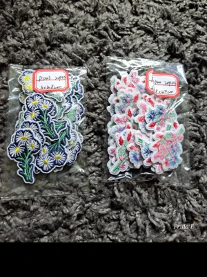 Broderade blom-applikationer 40 st - Två paket med broderade tygmärken i form av blommor. Ena paketet innehåller prästkragar i vitt, gult och grönt, det andra rosa och blå blommor med gröna blad. Perfekta att stryka eller sy fast på kläder, väskor eller accessoarer för en personlig touch.