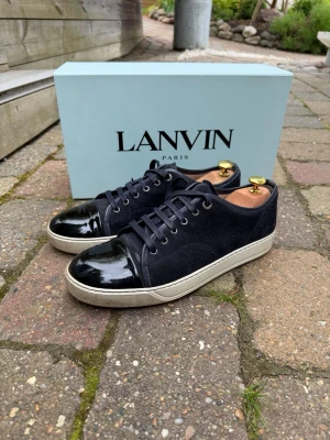 Lanvin navy captoe UK 8 (42) - Säljer mina mörkblå Lanvin Captoe (glansig cap). Köpta från Farfetch för 4499kr (kostar idag 5000kr nya). Skorna är något små i storleken så passar 42-43. De är i utmärkt skick förutom att det släppt  i hälkappan på båda skorna (se bild 5) går såklart att laga hos en skomakare. Tveka inte på att höra av dig vid eventuella frågor! 