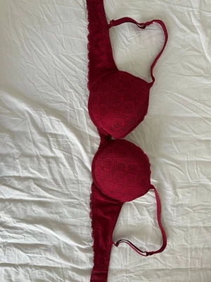 Limited edition intimissimi push up bh  - Snygg vinröd bh med vadderade kupor och spetsdetaljer på framsidan. Justerbara axelband och hakknäppning bak. Kuporna har ett diskret mönster i spetsen som ger en elegant look. Perfekt för dig som vill ha något både bekvämt och stilrent.