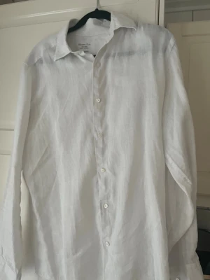 Vit linneskjorta från Massimo Dutti - Snygg vit skjorta i 100% linne från Massimo Dutti. Klassisk krage, knäppning framtill och lång ärm. Perfekt för en fräsch och stilren look. Skjortan är lätt och luftig, vilket gör den grym för varmare dagar.