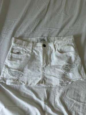 Vit kort jeanskjol från Hollister - Vit kort jeanskjol från hollister. I storlek 24, midjemåttet är ca 37cm.  Märket från bild 4a är från tidigare ägare, har inte testat få bort det. 