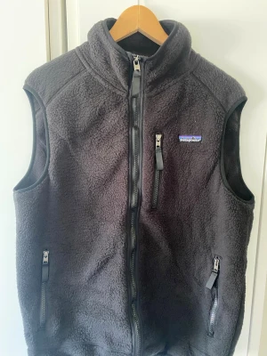 Patagonia vest i svart - snygg patagonia fleece vest i svart perfekt för lite kyligare dagar vesten är väldigt bekväm och är i storlek M perfekt för dig som är runt 175-180cm hör av er vid frågor!