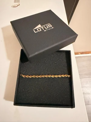 Guldarmband från Lotus Style - Snyggt guldarmband från Lotus Style med tvinnad kedja. Armbandet har en elegant och stilren design som passar perfekt till alla tillfällen. Levereras i original ask. Materialet ser ut att vara metall med guldfinish. 4MM 21CM