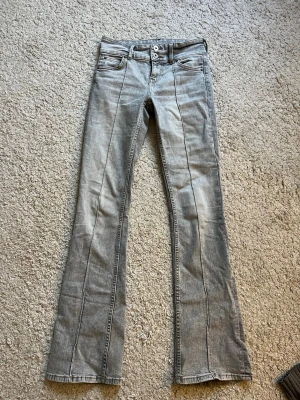 Lågmidjande jeans - Säljer ett par gråa jeans från Bershka med utsvängda ben och pressveck framtill. ❤️