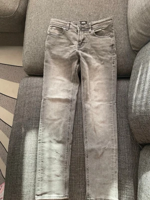 Grå slim fit jeans Jack & Jones - Snygga grå slim fit jeans från Jack & Jones med klassisk femficksdesign och dragkedjegylf. Jeansen har en tvättad look och raka ben, perfekta till en avslappnad stil. Materialet är mjukt och stretchigt för extra komfort.
